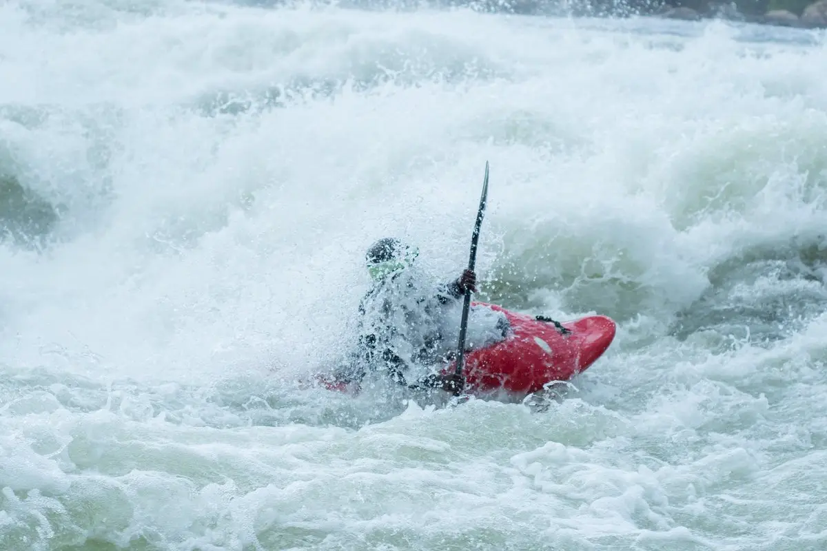 Kayaker paddling through foaming whitewater