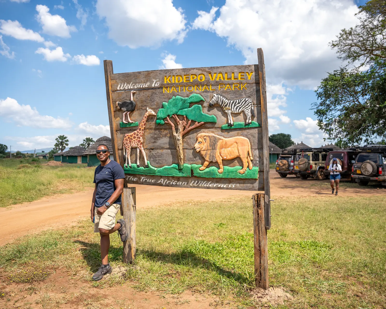 Visitor standing beside the Kidepo Valley National Park entrance sign