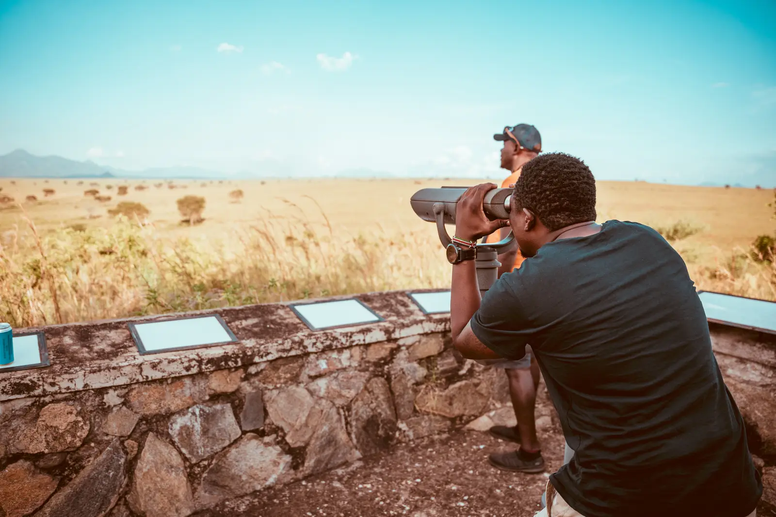 Visitors looking out over a wide, dry grassland from a viewpoint
