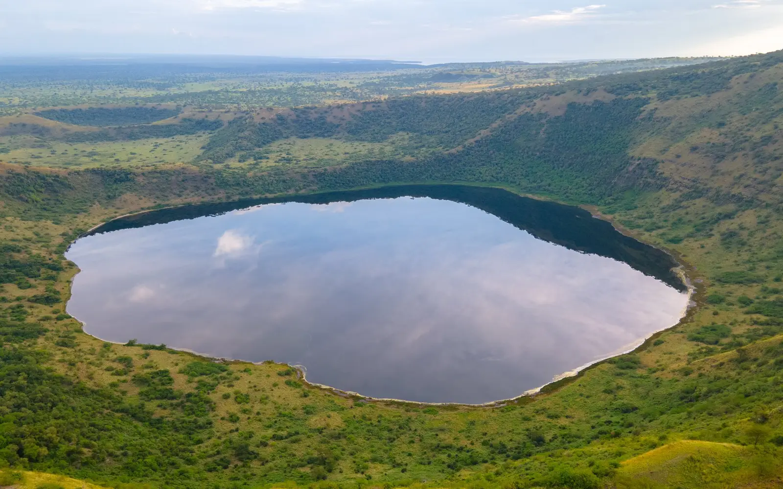 Aerial view of a crater lake surrounded by green hills