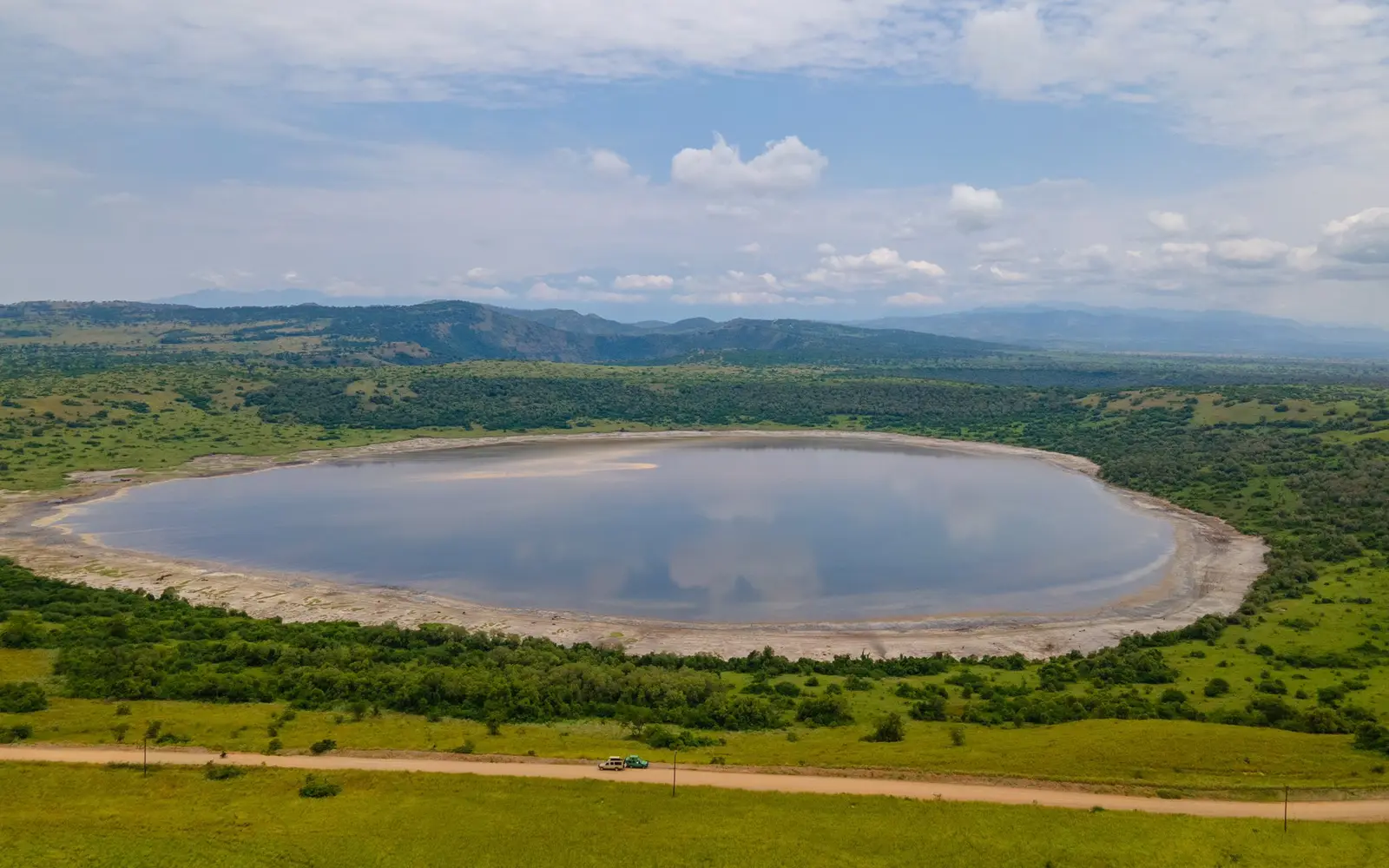 Aerial view of a lake framed by green hills and grassland