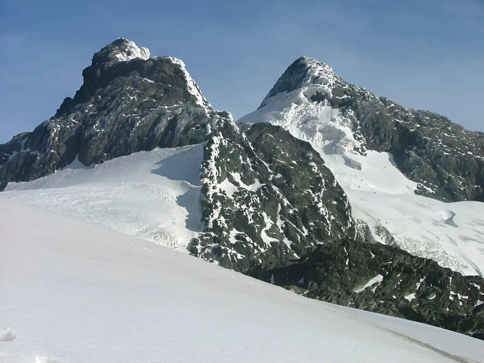 Two rocky peaks rising above snow-covered mountain slopes